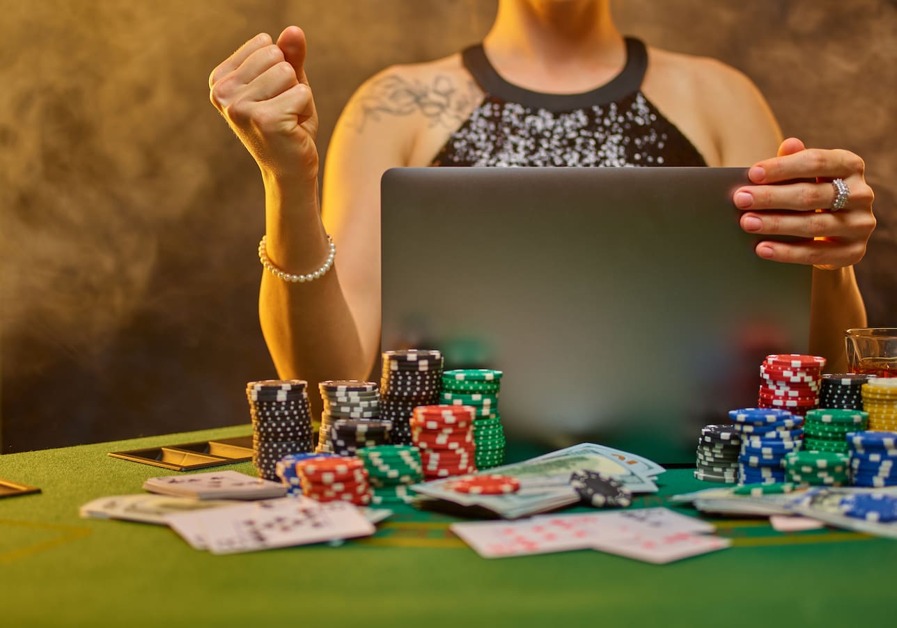 Девушка, играющая в лайв-казино на компьютере, с фишками и картами на столе